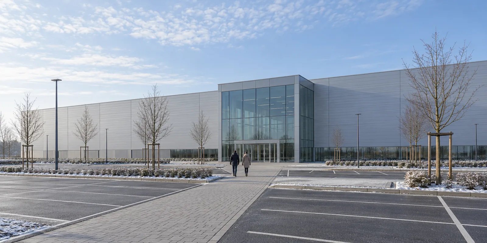 Visitors walking towards the glass entrance of a large exhibition hall on a winter morning